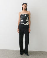 A person wearing a patterned strapless top and pants, standing on a plain background.