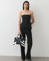 Person in strapless top and pants holding handbag with patterned scarf.