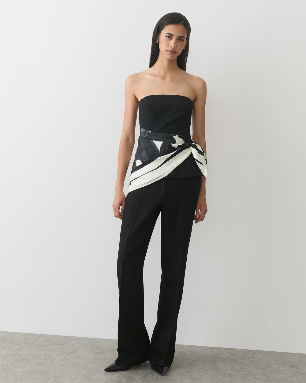 Person wearing a strapless top and pants with a patterned wrap.