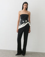 Person wearing a strapless top and pants with a patterned wrap.