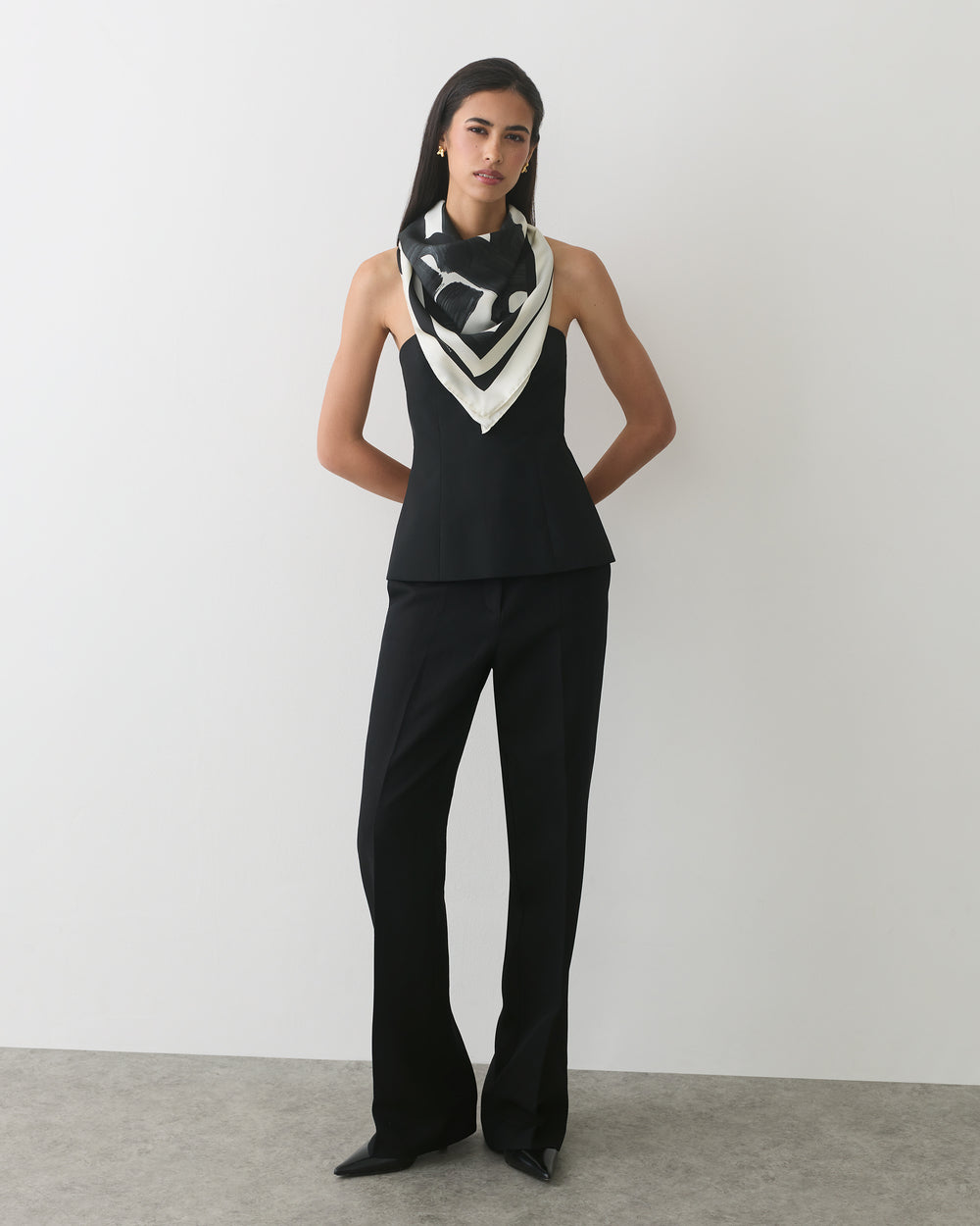 Person wearing a sleeveless top, long pants, and a patterned scarf.