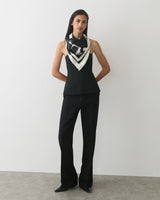 Person wearing a sleeveless top, long pants, and a patterned scarf.