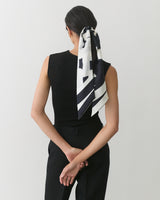 Person facing away with scarf tied around ponytail, arms behind back.