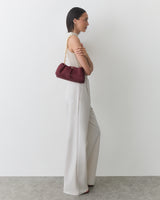 Person holding a small purse with a chain strap, wearing sleeveless top and wide-leg pants.