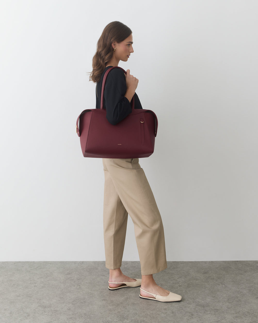 Person carrying handbag and wearing relaxed fit pants with slip-on shoes