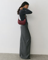 Person in long pants, long sleeve top, holding a small shoulder bag.