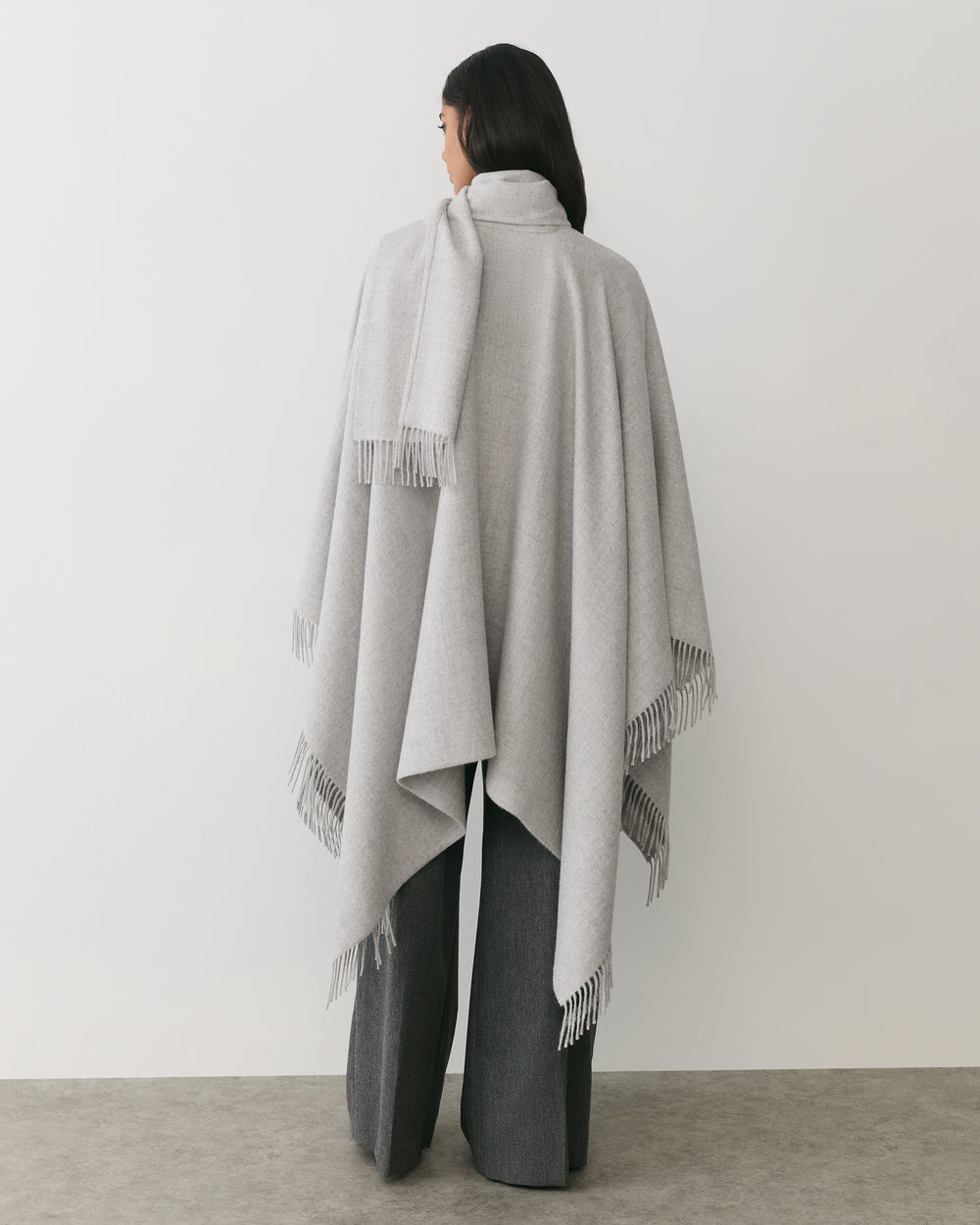 Person wearing a long cape standing with back to the camera.