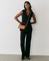 Person in a sleeveless top and pants with a small shoulder bag.