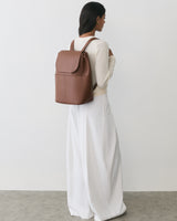 Person wearing a long outfit with a backpack standing to the side.
