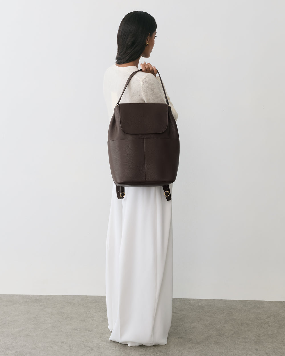 Person standing with a large bag over shoulder, back facing the camera.