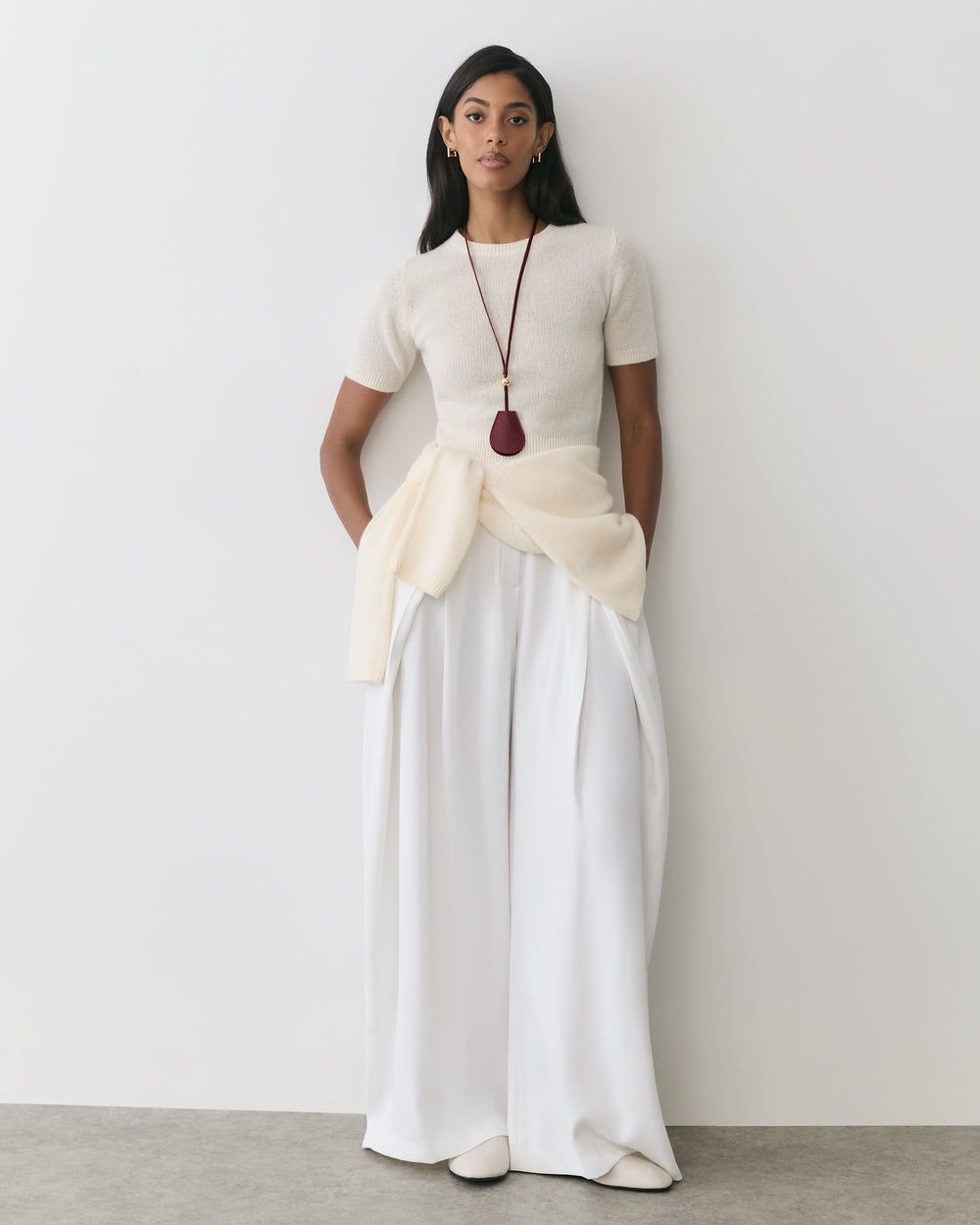 Person wearing a short-sleeve top with wide-leg pants and a long necklace.
