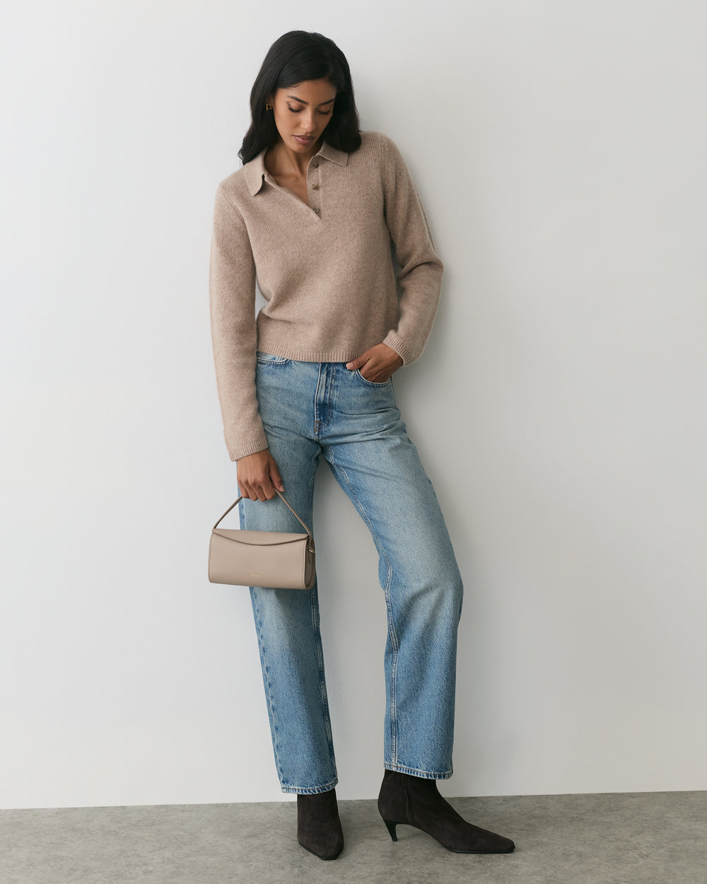 Person in casual outfit holding a small handbag