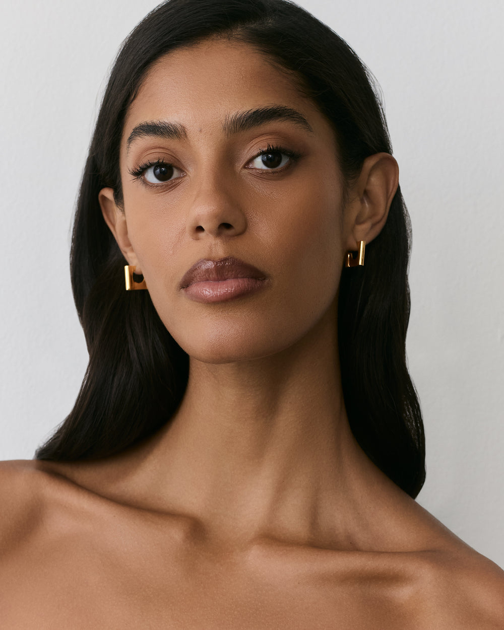 Person wearing geometric earrings with bare shoulders visible.