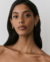 Person wearing geometric earrings with bare shoulders visible.