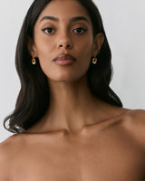 Person wearing geometric earrings with a neutral expression