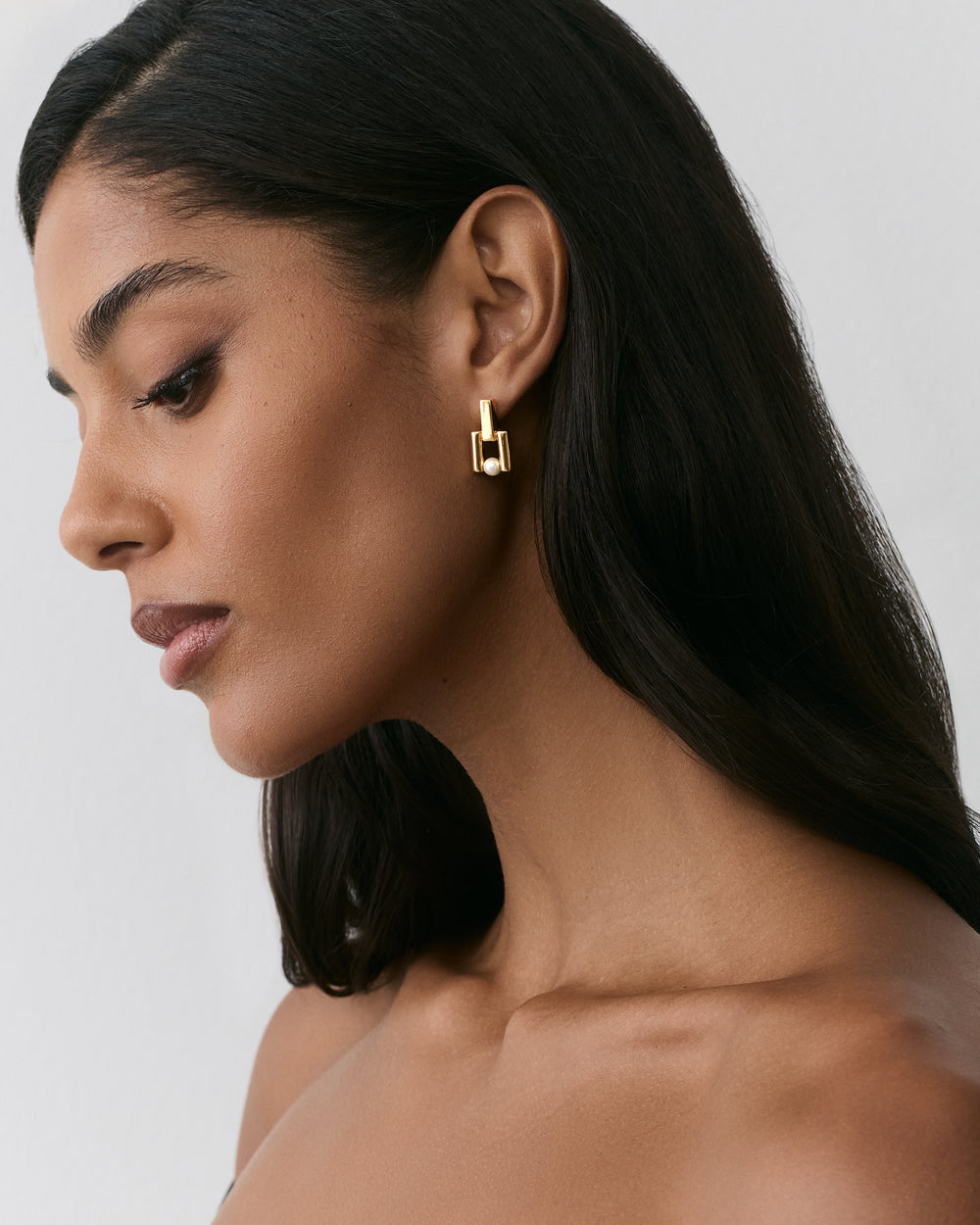 Person wearing geometric earrings looking sideways