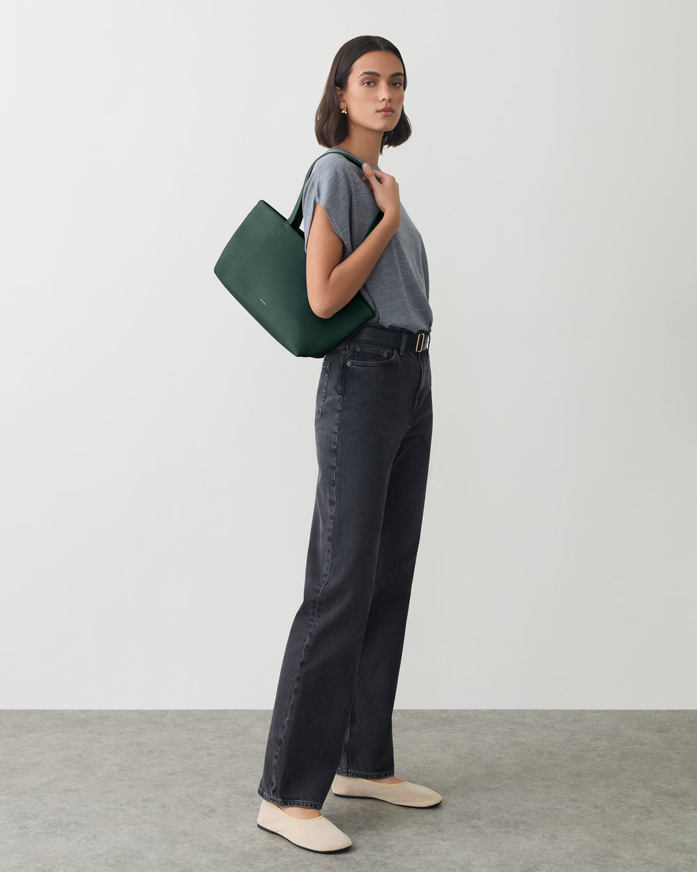 Person in casual outfit holding a shoulder bag.