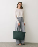 Person wearing long-sleeve shirt and jeans holds a large bag.