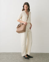 Person in a V-neck top and wide-leg pants with a shoulder bag.