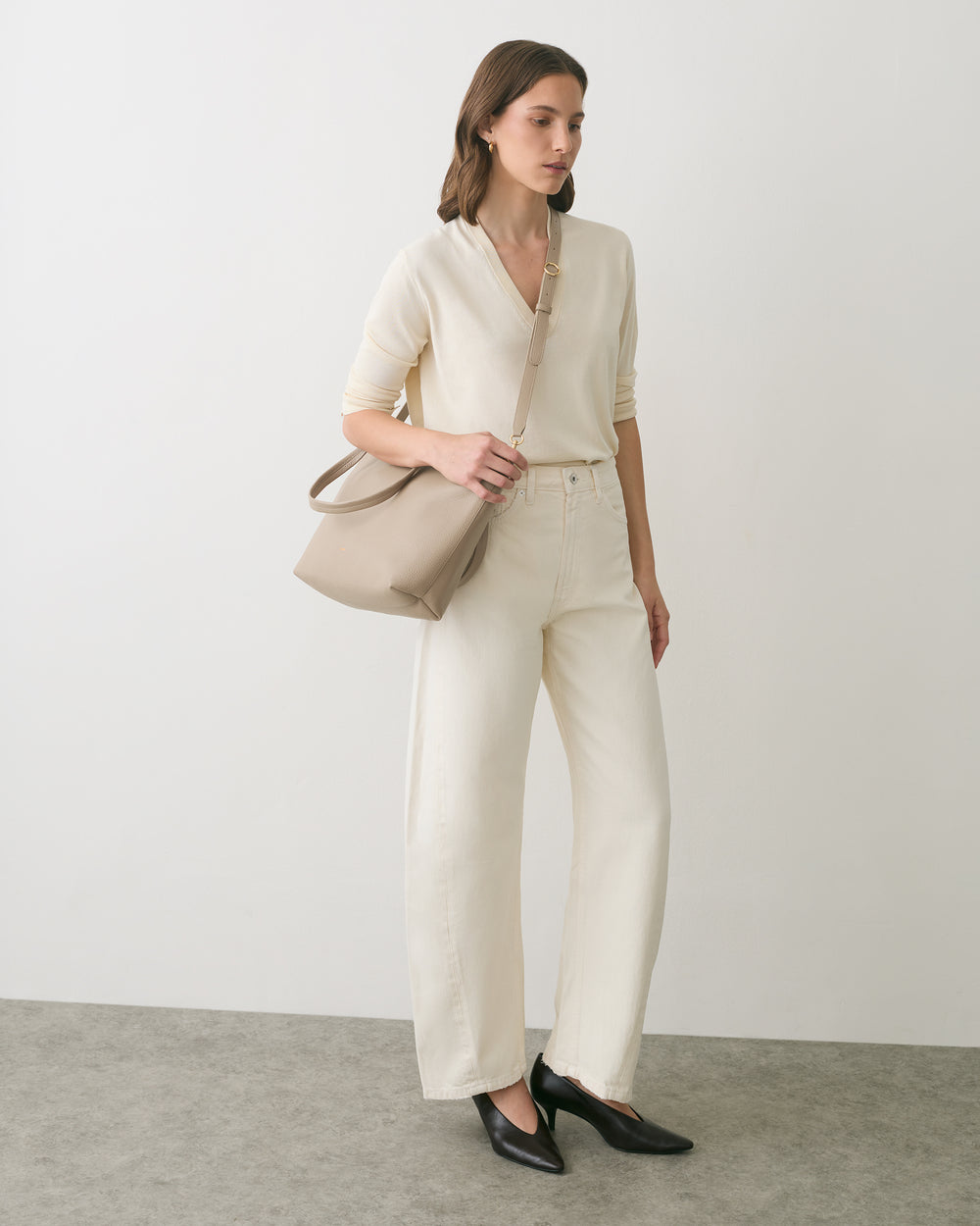 Person standing with a shoulder bag and wearing casual outfit