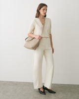 Person standing with a shoulder bag and wearing casual outfit