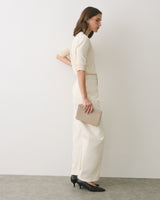 Person in outfit holding a rectangular clutch, standing sideways.
