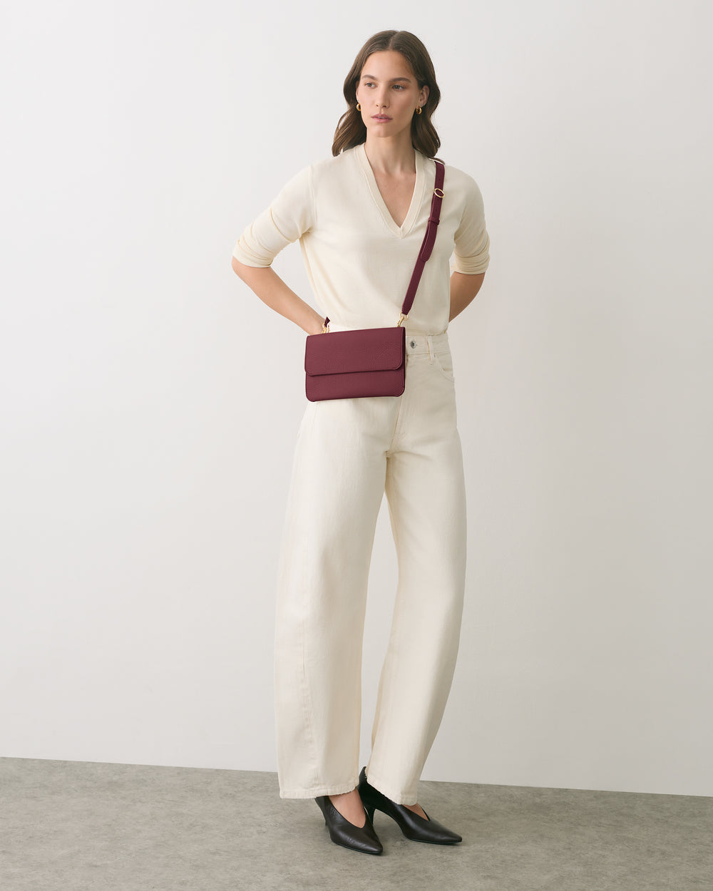Person in a long-sleeve top and pants, wearing a small crossbody bag and heels.
