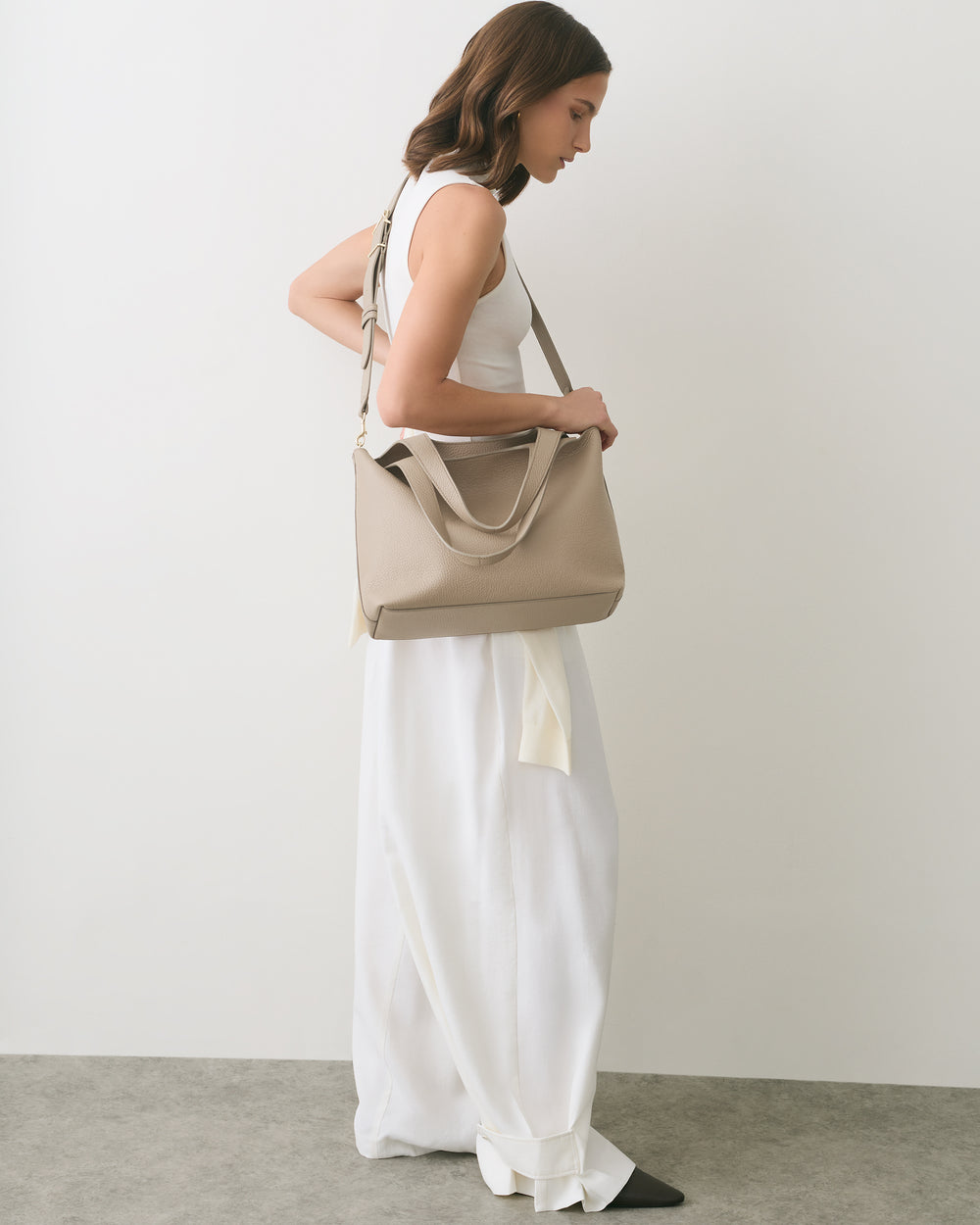 Woman in a sleeveless top and long skirt carrying a shoulder bag.
