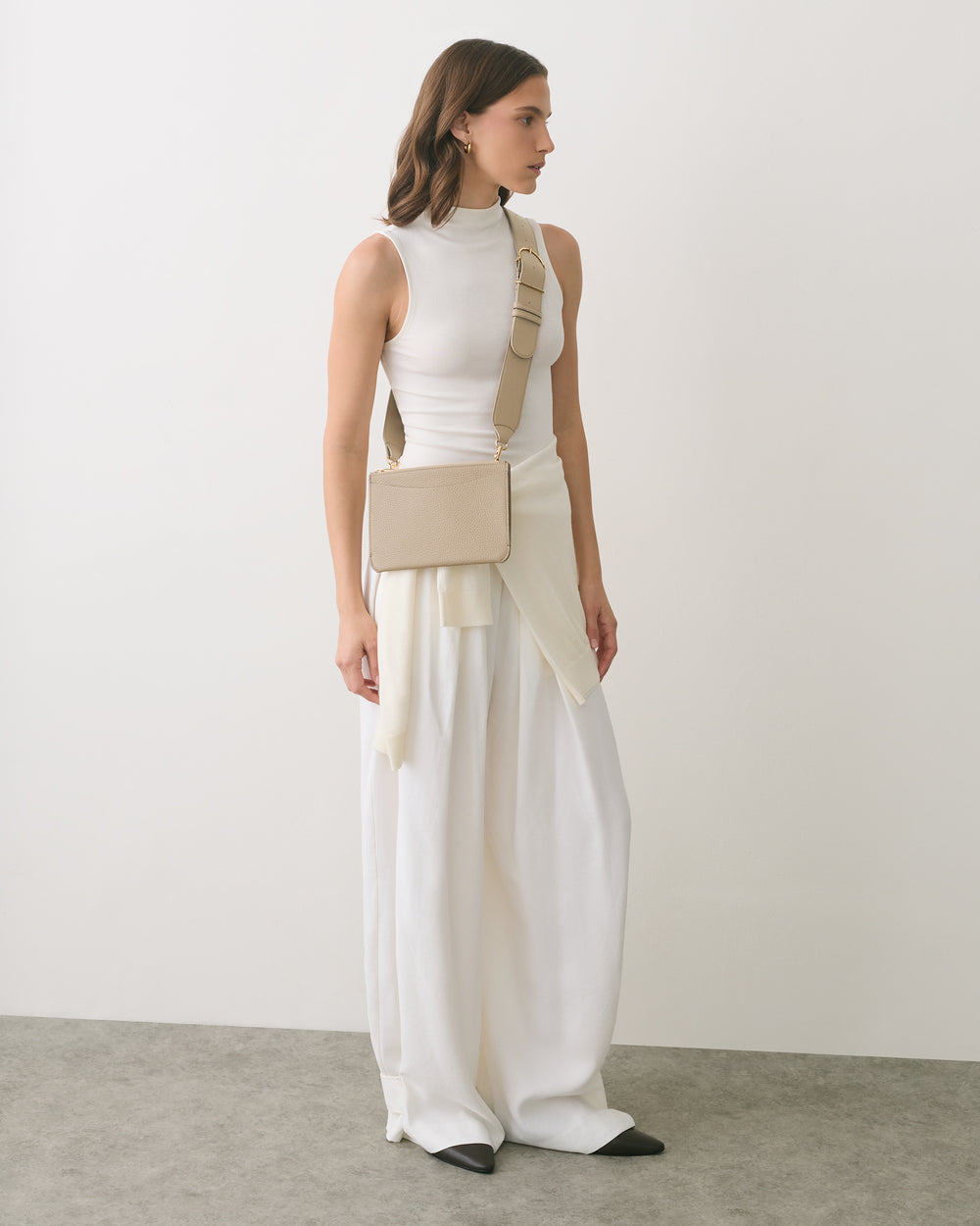 Person wearing a sleeveless top, wide pants, and a belt bag.