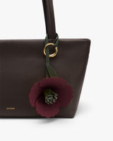 A handbag with a flower keychain attached to the handle.