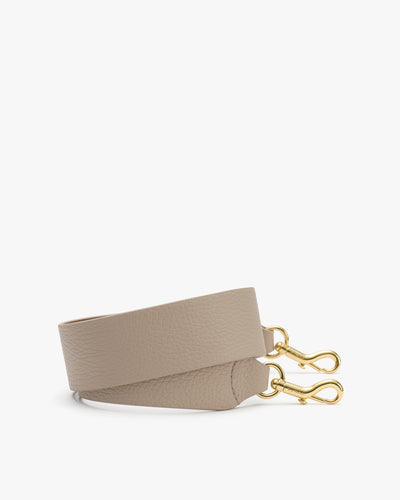 Bag strap with gold clips lying flat.