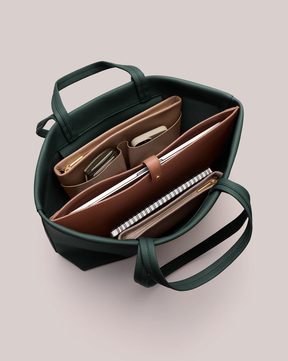 Open tote bag with organized compartments holding notebooks and pouches.