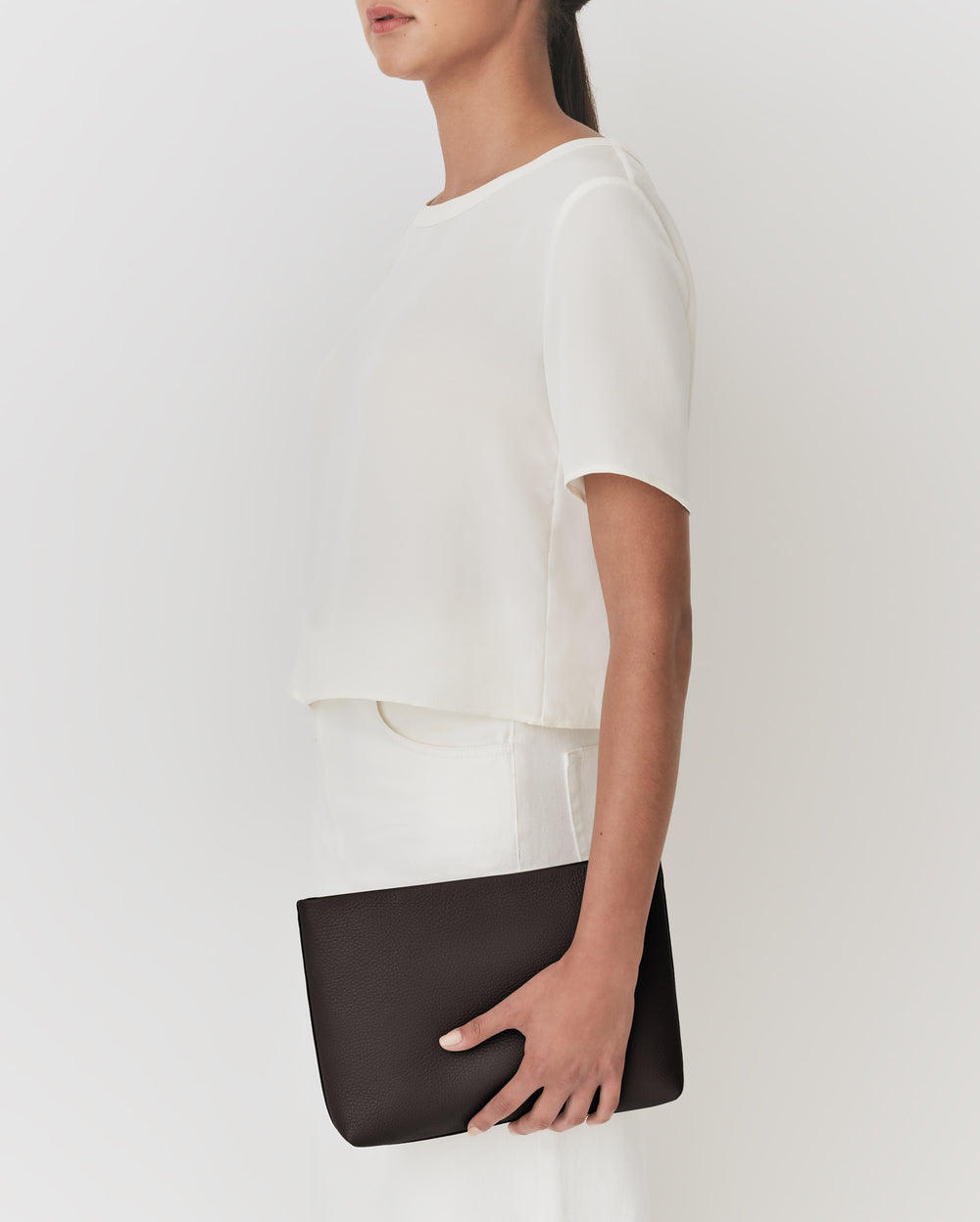 Person holding a rectangular clutch bag.