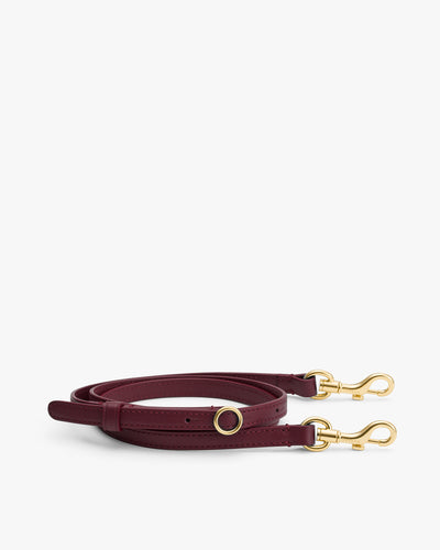 Long leather strap with gold clasps and ring details.