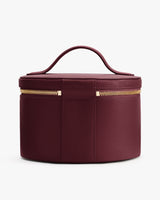 Round textured leather handbag with handle and zipper.