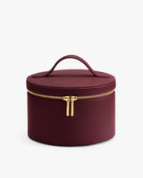 Round leather vanity case with a handle on the lid and a zipper closure.