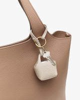 A close-up of a bag with a key attached to its strap.