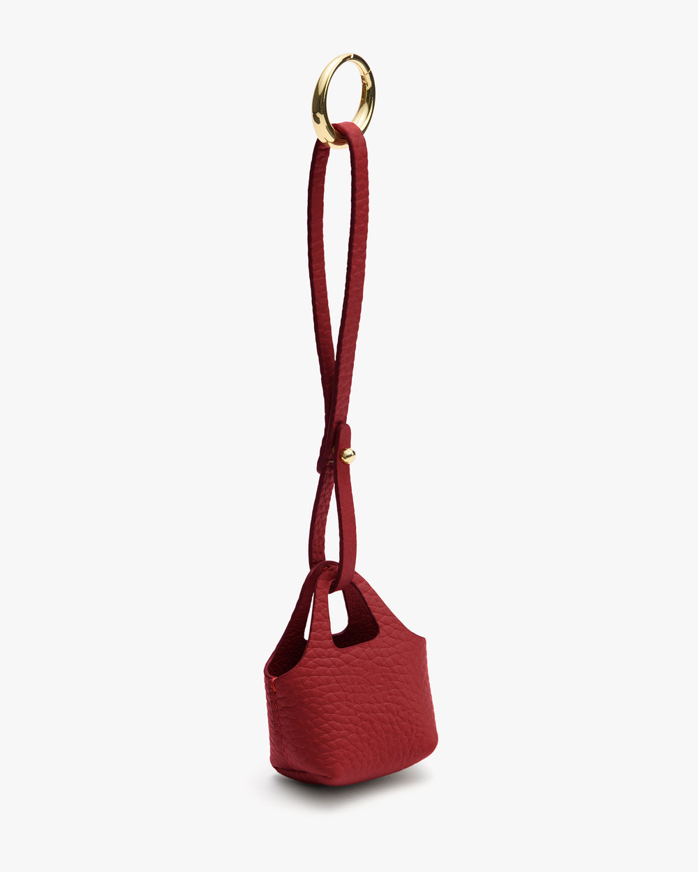 Small textured bag with long loop handle and circular metal accent.