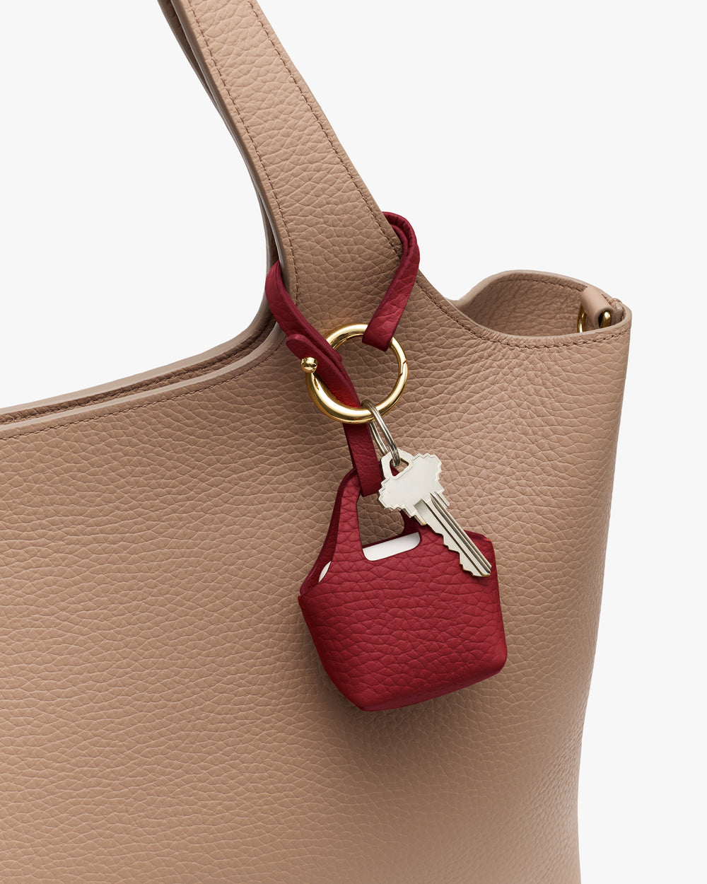 Bag with a small red accessory holding keys on the strap.