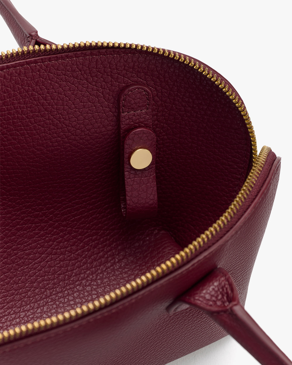 Open handbag with textured interior and zipper closure.