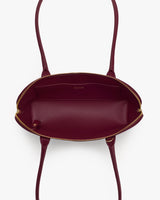 Open handbag with two handles and a zippered top view.