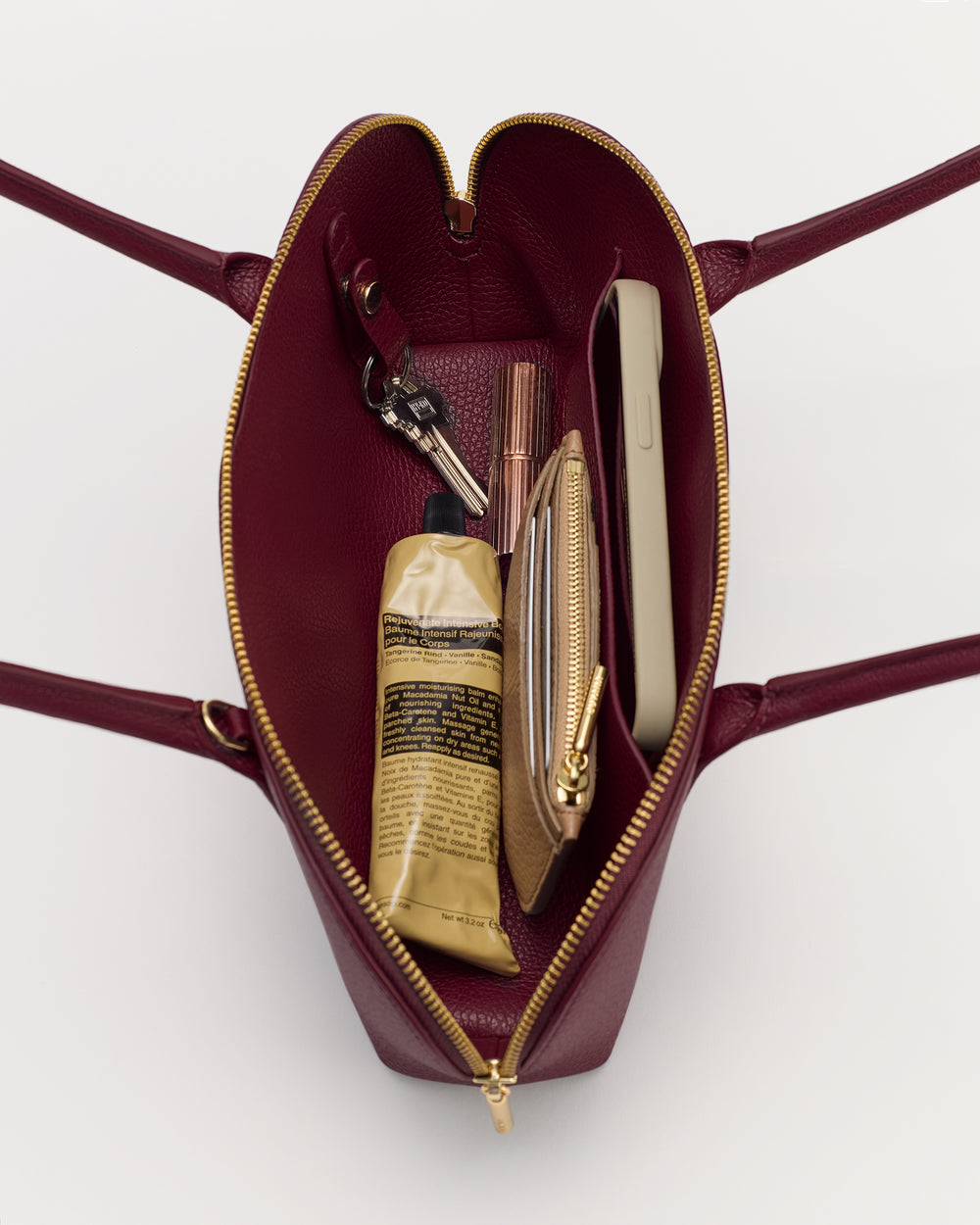 Open handbag with visible items like keys, a phone, a tube, and a small pouch inside.