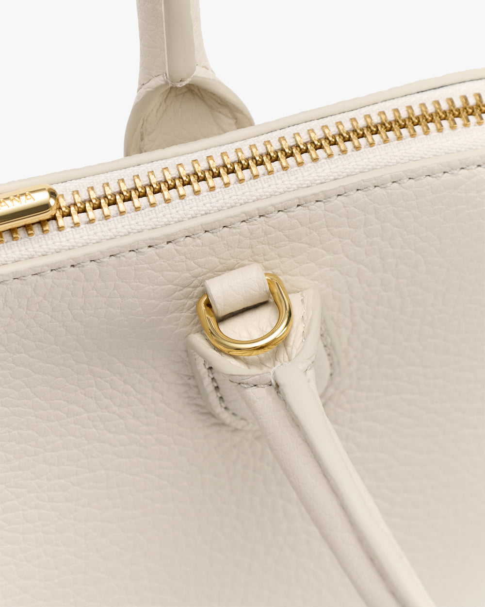 Close-up of a textured bag with a zipper and metal ring connection.