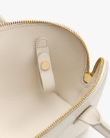 Open handbag with zipper and buttoned strap inside.