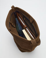 Open bag containing books, a laptop, and a plaid fabric piece.