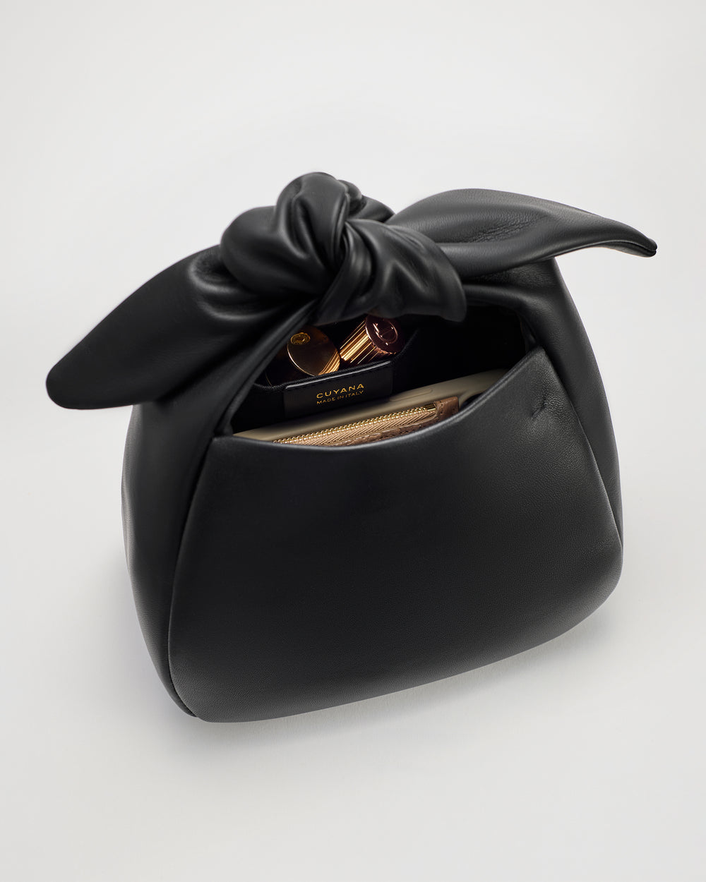 Handbag with a knotted top and items peeking from the open pocket