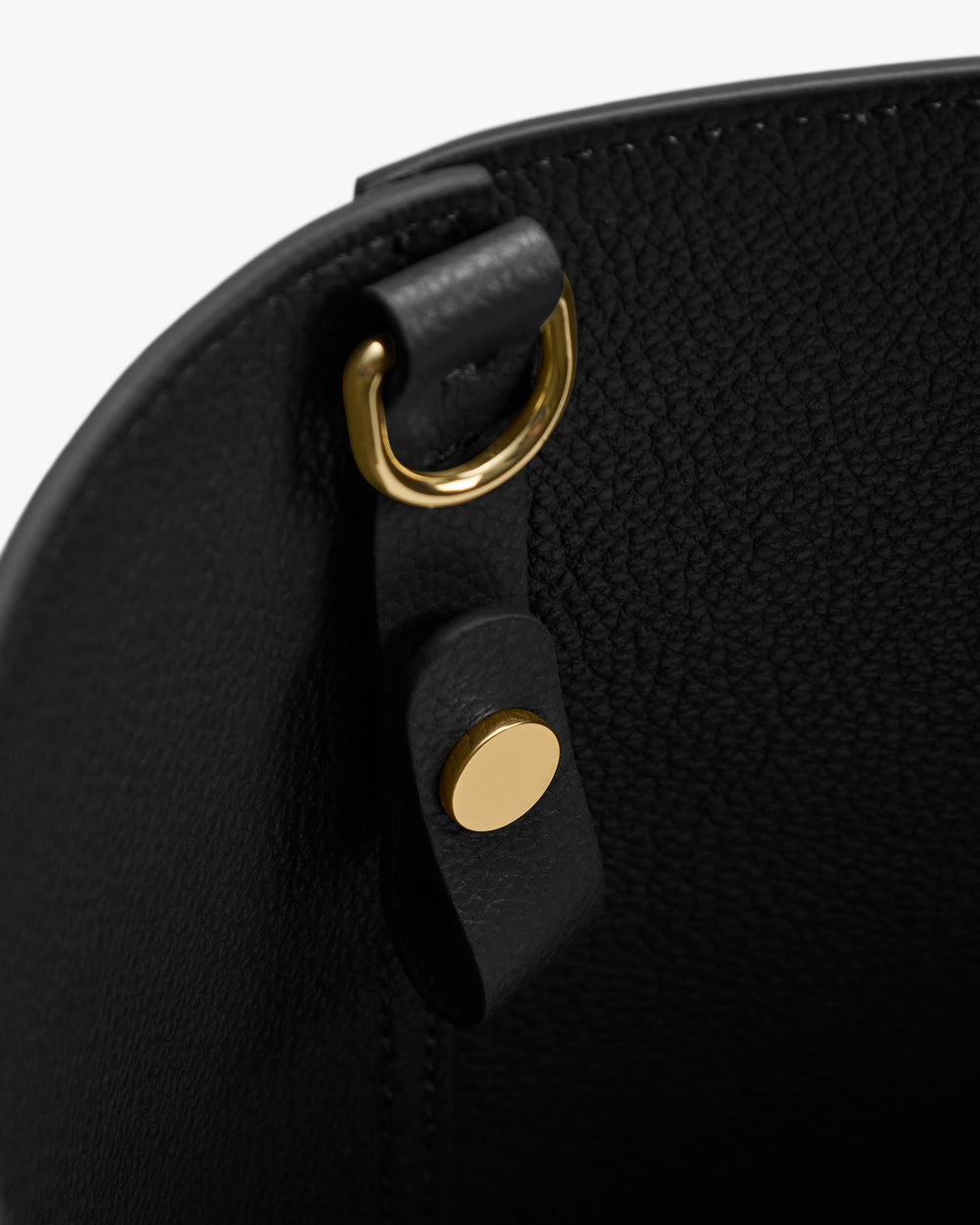 Close-up of a bag's inner D-ring and button detail.