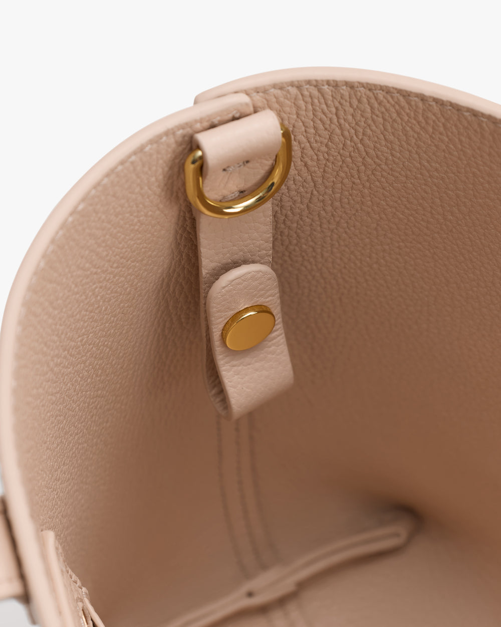 Bag interior with a metal ring and snap button on a strap.