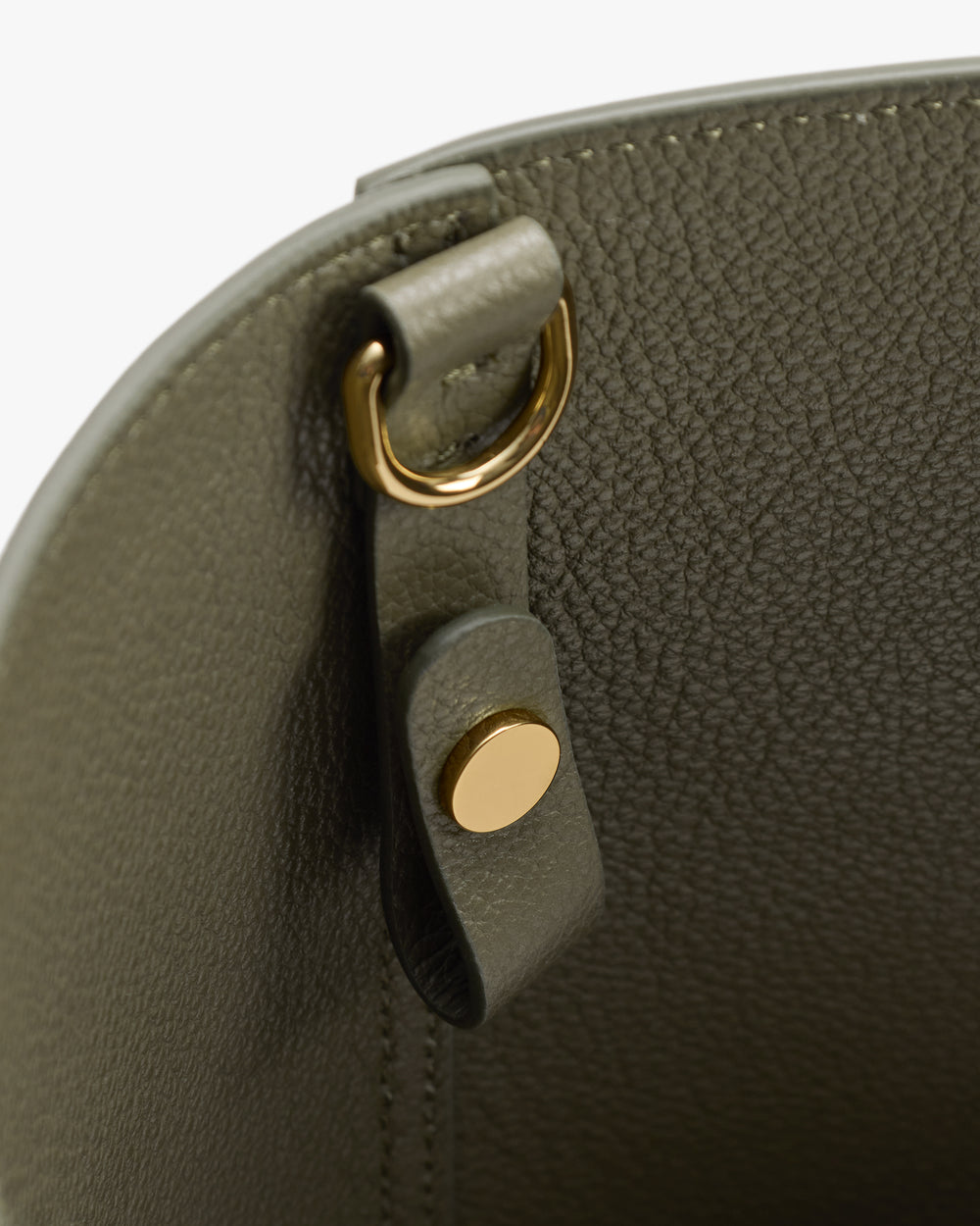 Close-up of a bag's metal ring and button detail.