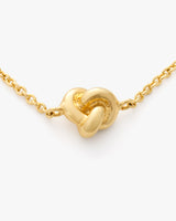 A necklace with a knot-shaped pendant on a chain.